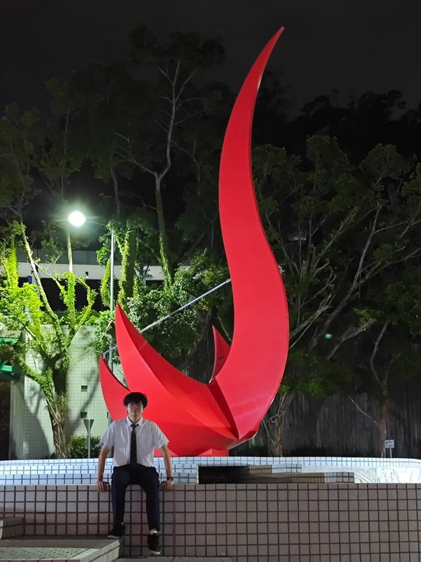 Owen sitting in front of the red bird sculpture at night